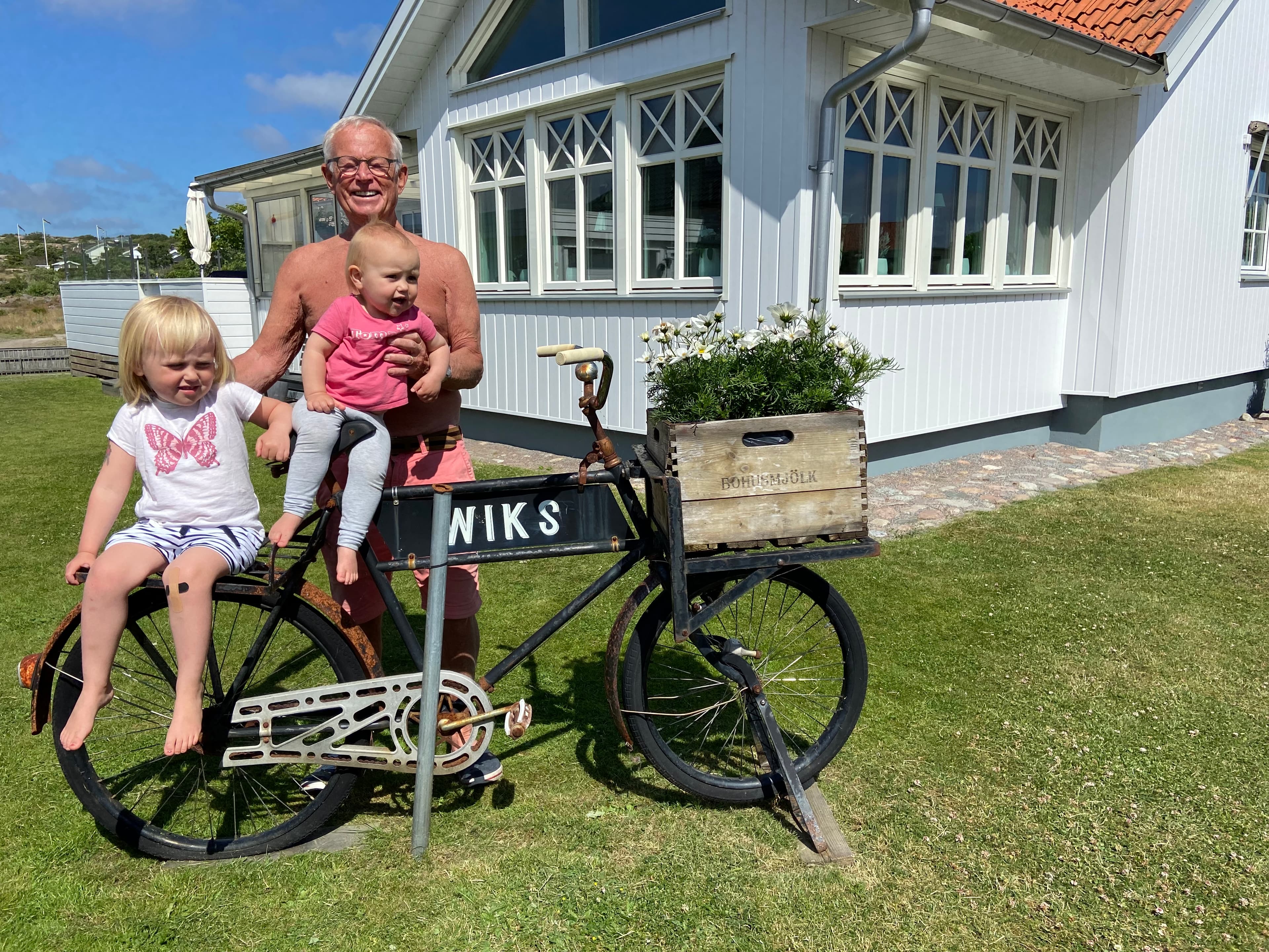 Tommy Wik med sina barnbarn på en gammal cykel framför huset med OnceWall-fasad