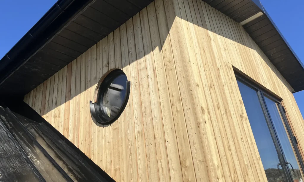 Takfot klädd i OnceWall antracitpanel mot en traditionell träfasad
