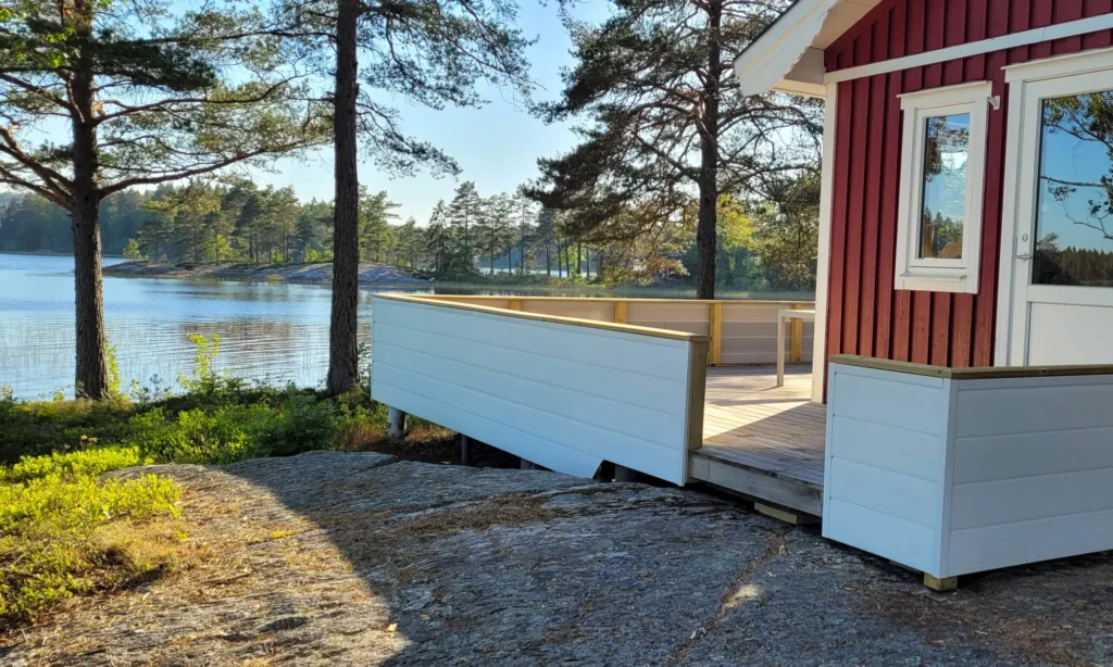 Röd stuga med OnceWall fasad vid sjökanten